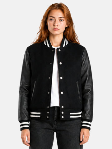 Woman wearing an all black varsity jacket with leather sleeves and striped trims