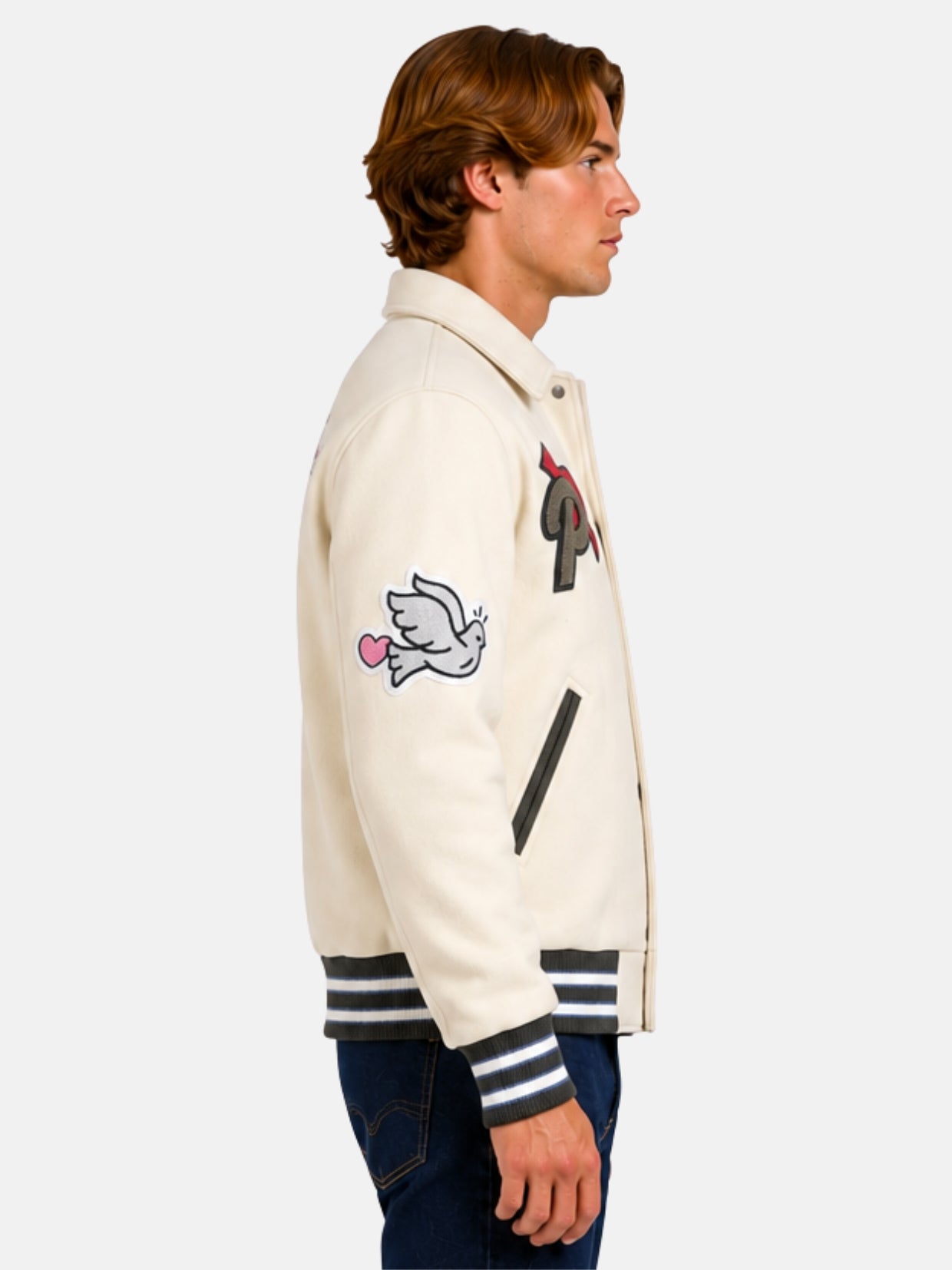 Side profile of beige varsity jacket showing dove and heart sleeve patch