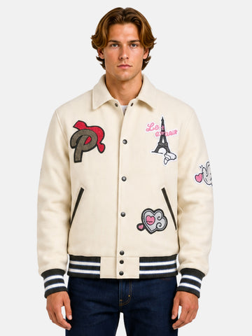 Man wearing a beige varsity jacket with embroidered Paris patches and shirt collar