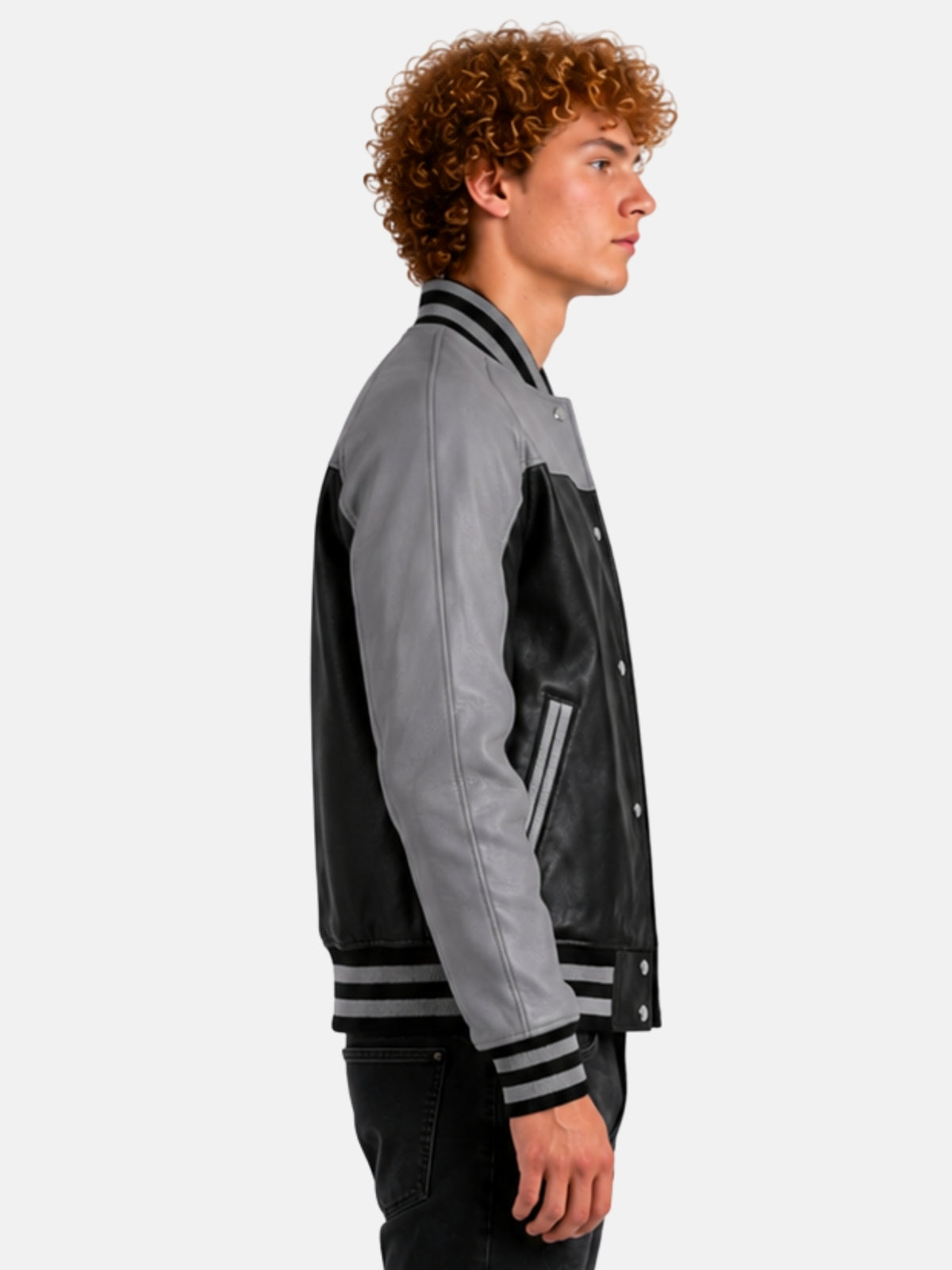 Side profile of black leather varsity jacket showing grey raglan sleeve and striped knit cuff