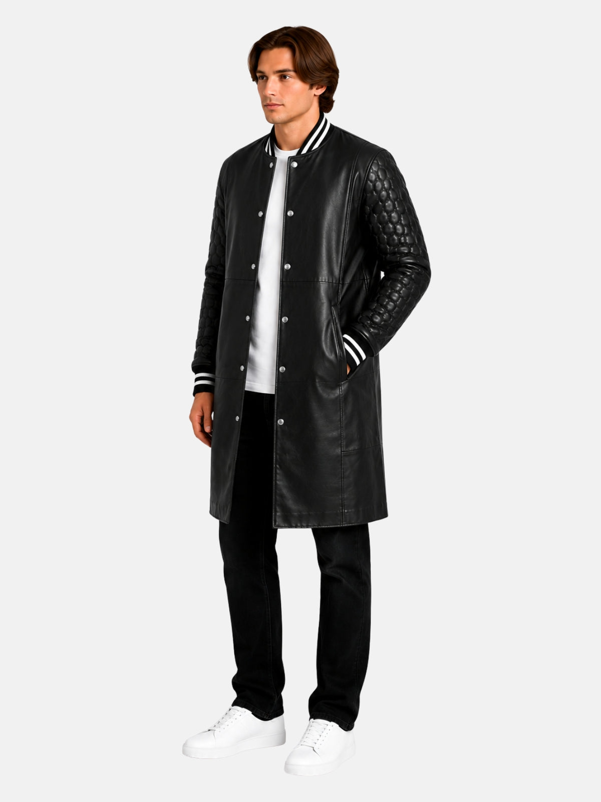 Model in knee-length black leather varsity coat with quilted sleeves, hand in pocket