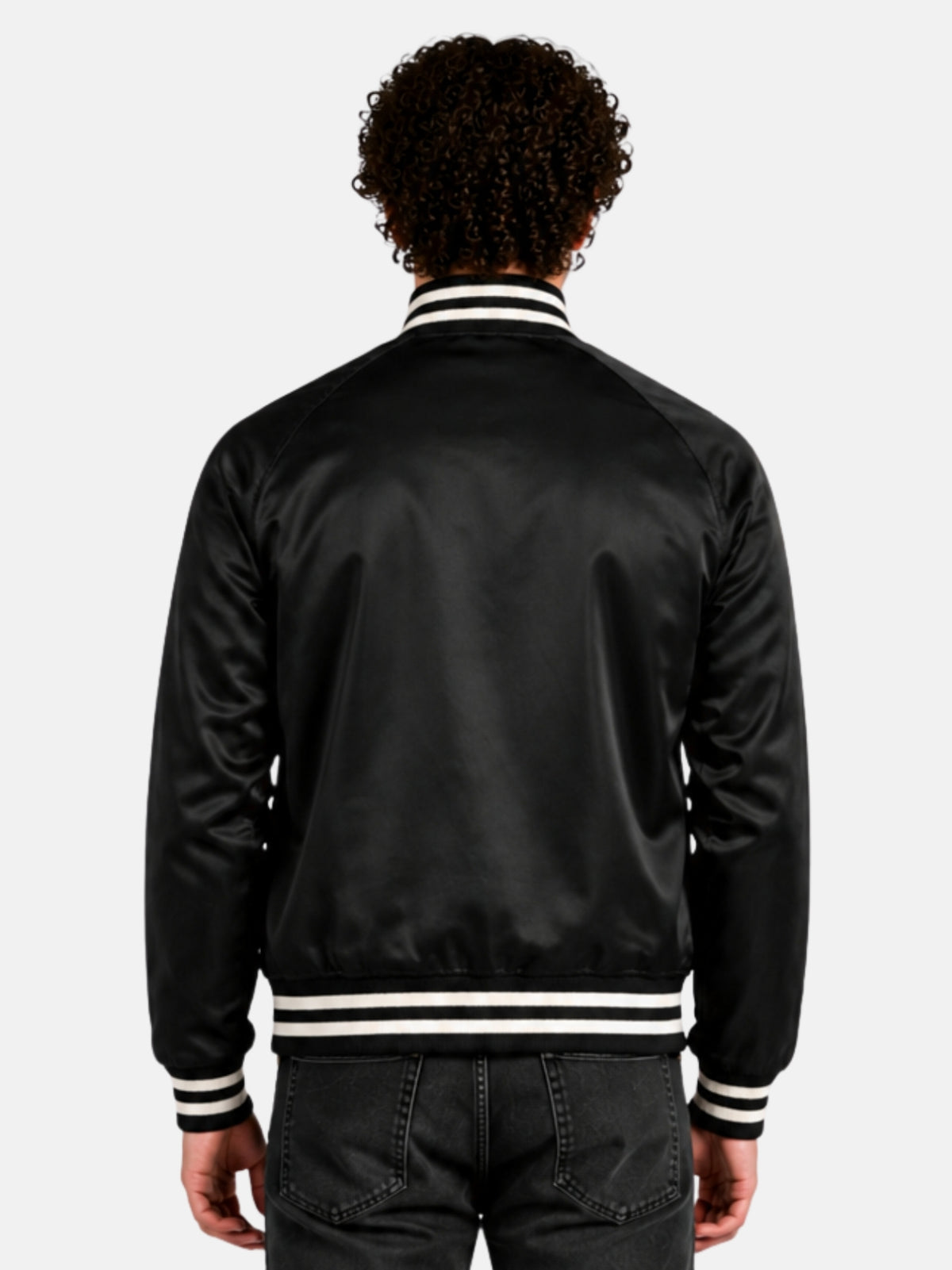 Back view of a black satin varsity jacket showing raglan sleeve seams on model