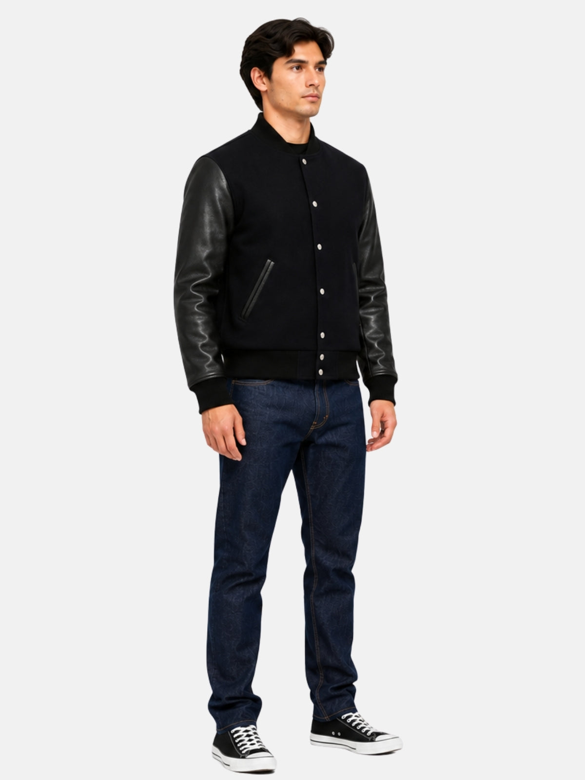 All-black varsity bomber styled with raw indigo denim and black low-top sneakers, full-length look