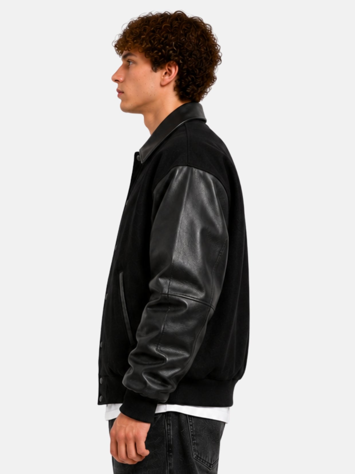 Side profile of a black varsity jacket with smooth leather sleeves on model