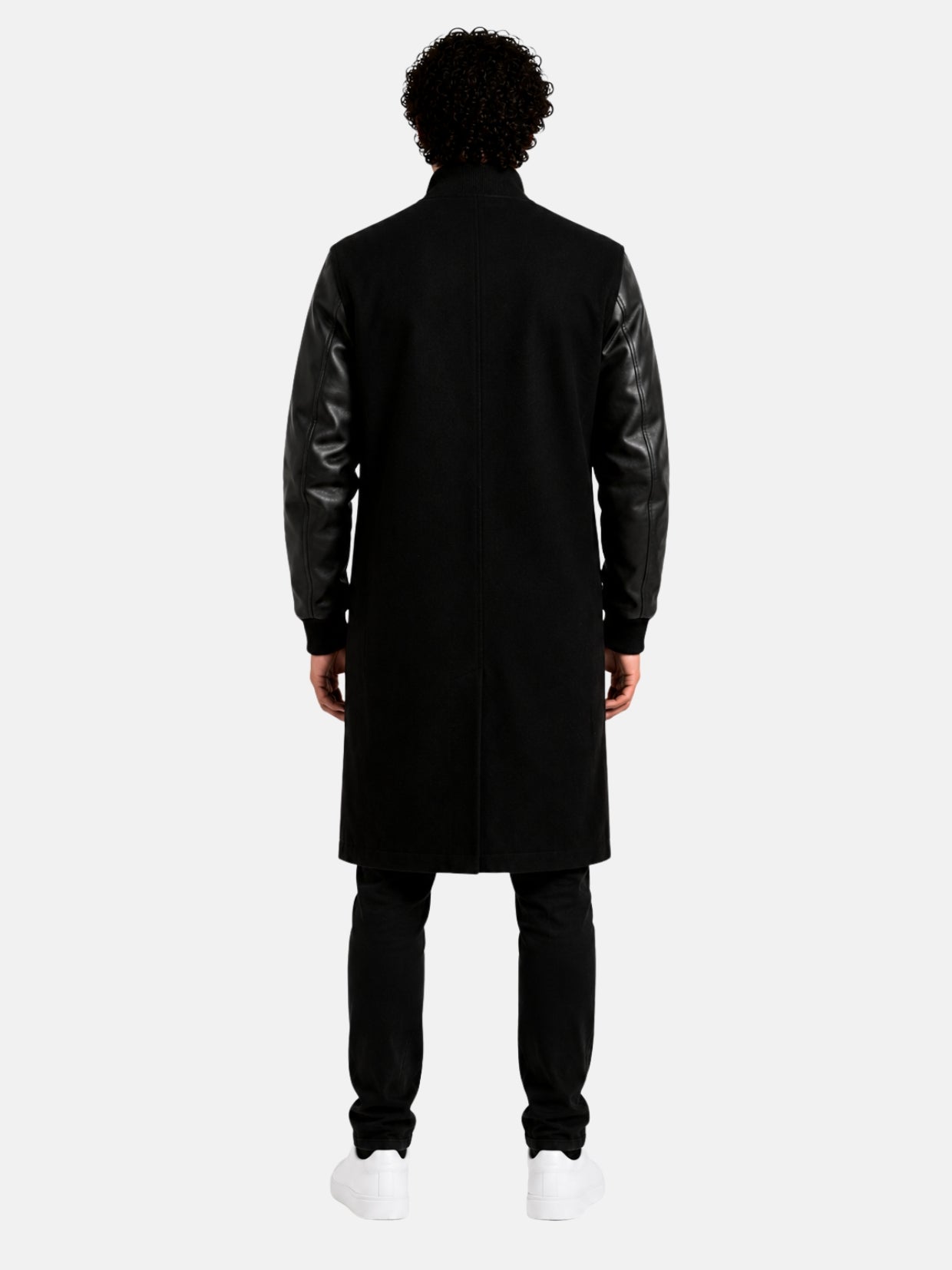 Back view of knee-length black wool varsity coat with leather sleeves on model