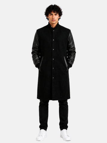Man wearing knee-length black wool varsity coat with leather sleeves and snap front