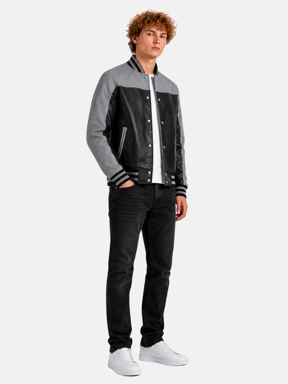 Full-length view of grey and black leather varsity jacket styled with black jeans and white sneakers