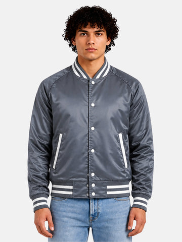 Man wearing a grey satin varsity jacket with white striped trims and snap front