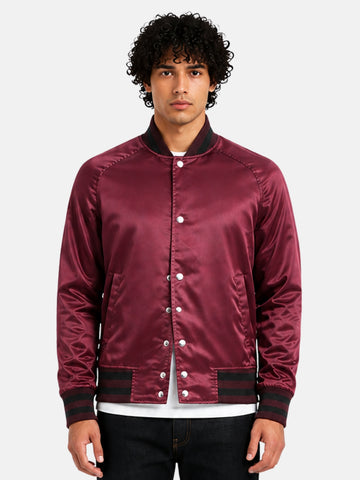 Man wearing a maroon satin varsity jacket with black ribbed trims and silver snaps