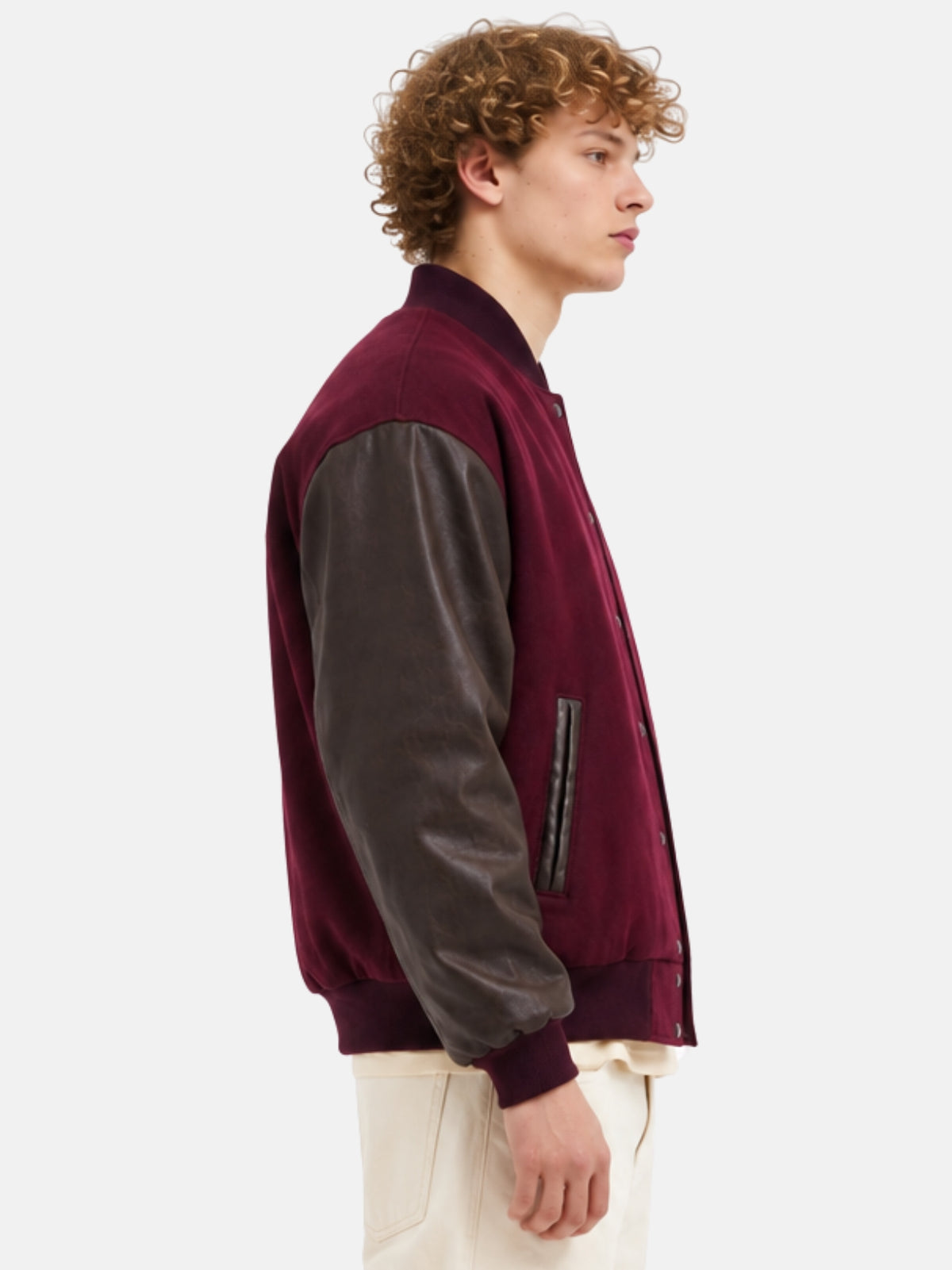 Side profile of a maroon varsity jacket with dark brown leather sleeves on model