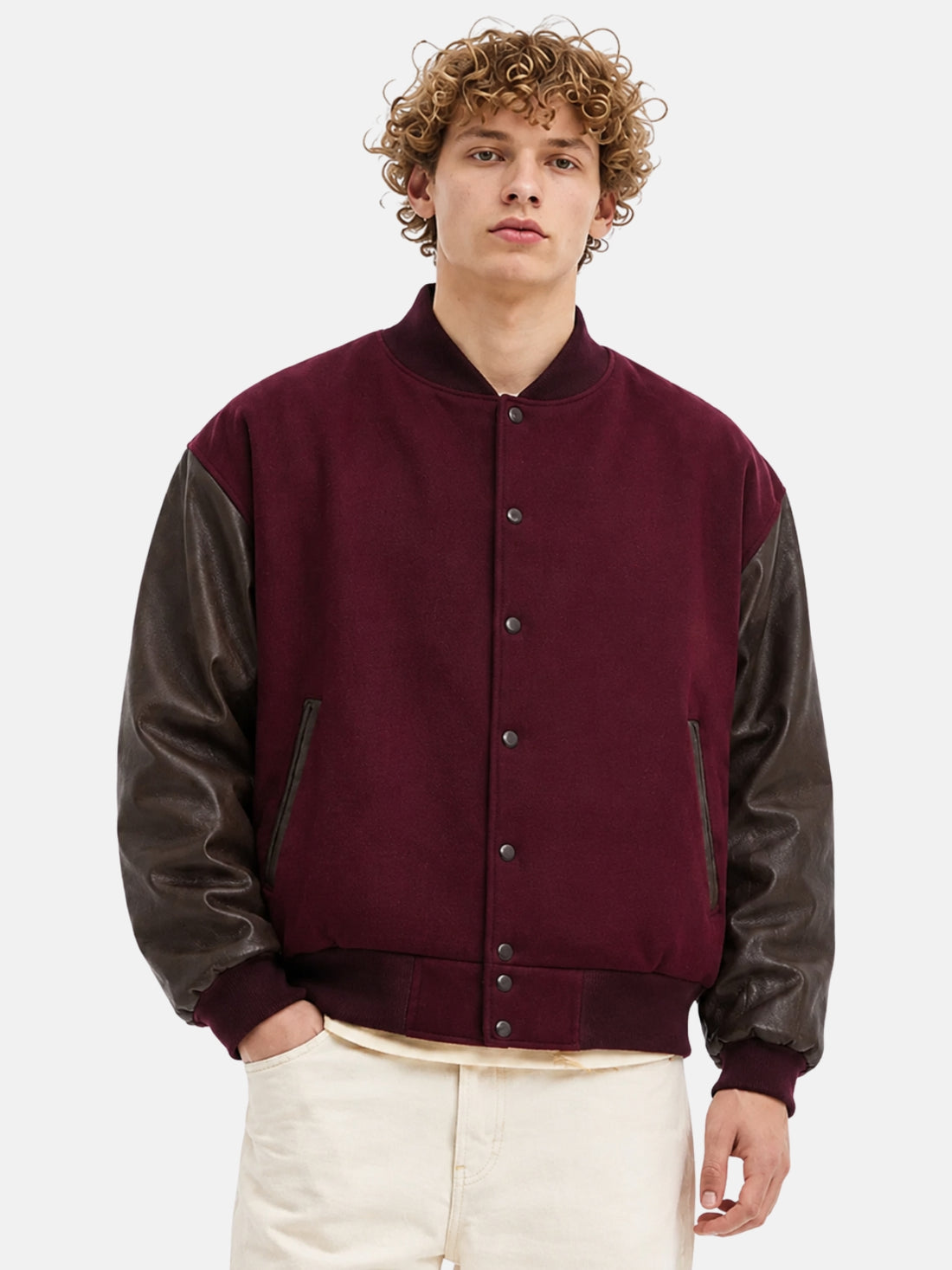 Man wearing a maroon wool varsity jacket with dark brown leather sleeves and snap front