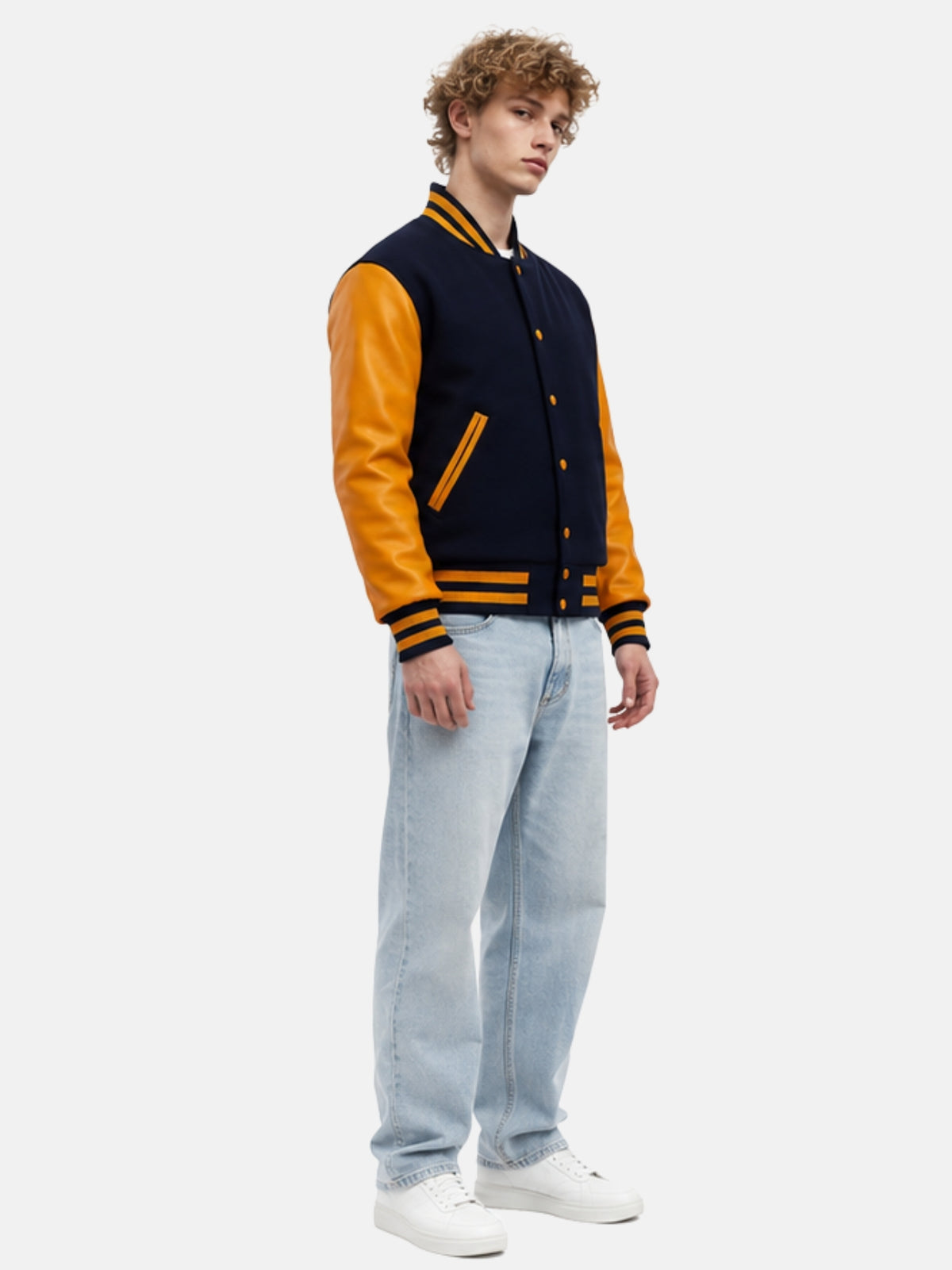 Full-length streetwear outfit pairing navy and gold letterman jacket with light-wash jeans and white sneakers