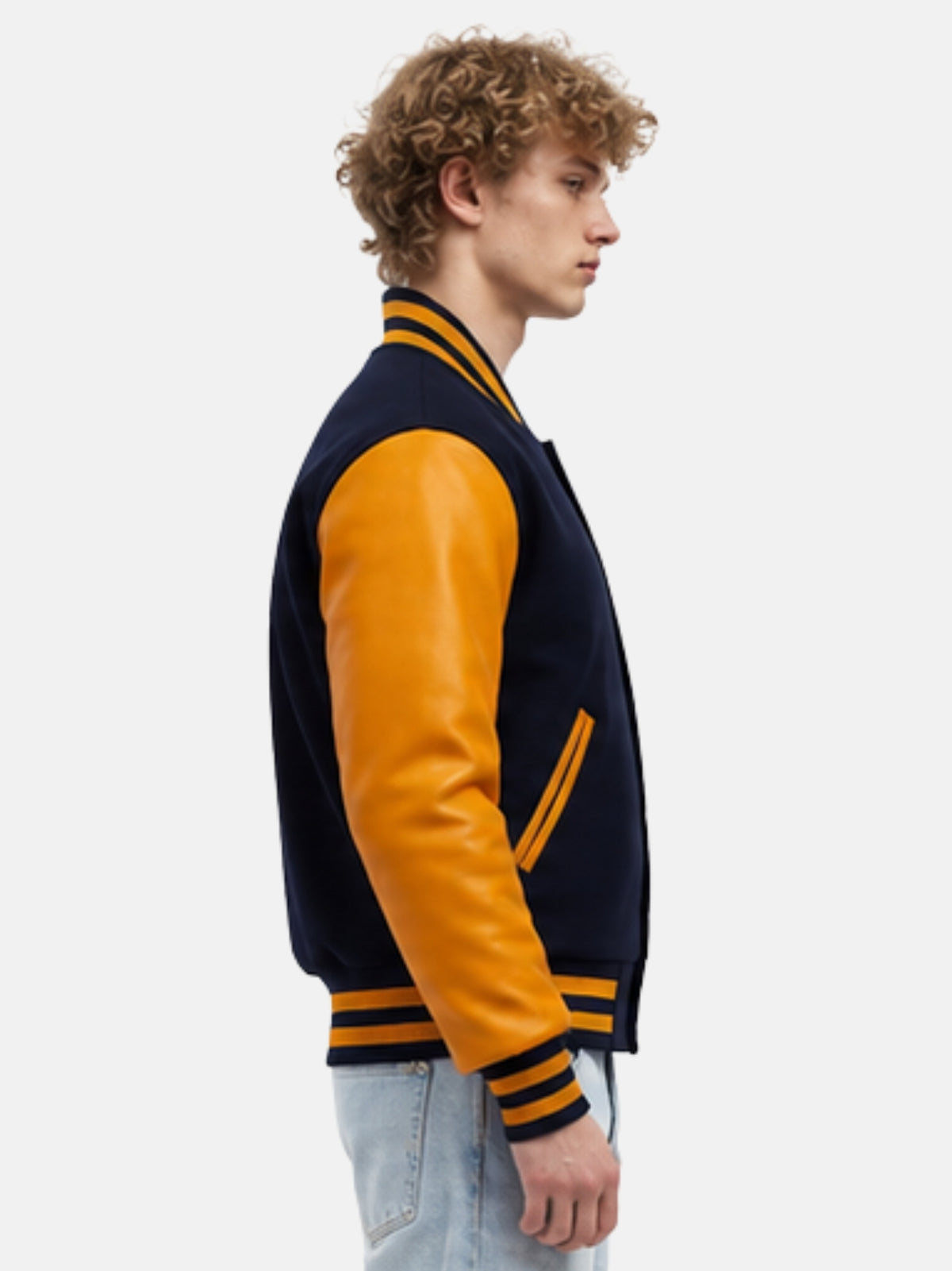 Side profile showing gold cowhide leather sleeve and striped knit cuff on navy baseball-collar jacket