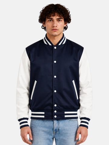 Man wearing a navy satin varsity jacket with white sleeves and striped rib trims, front view