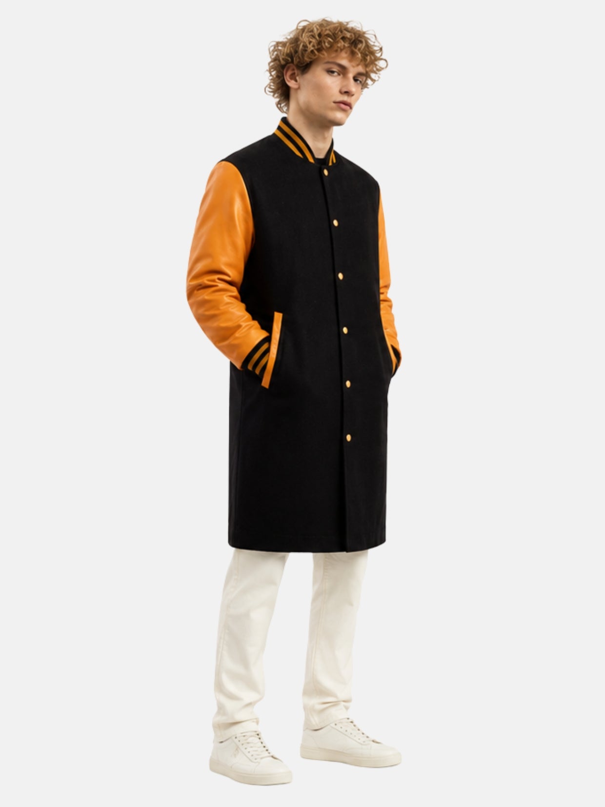 Model in long black letterman coat with orange leather sleeves and striped rib collar