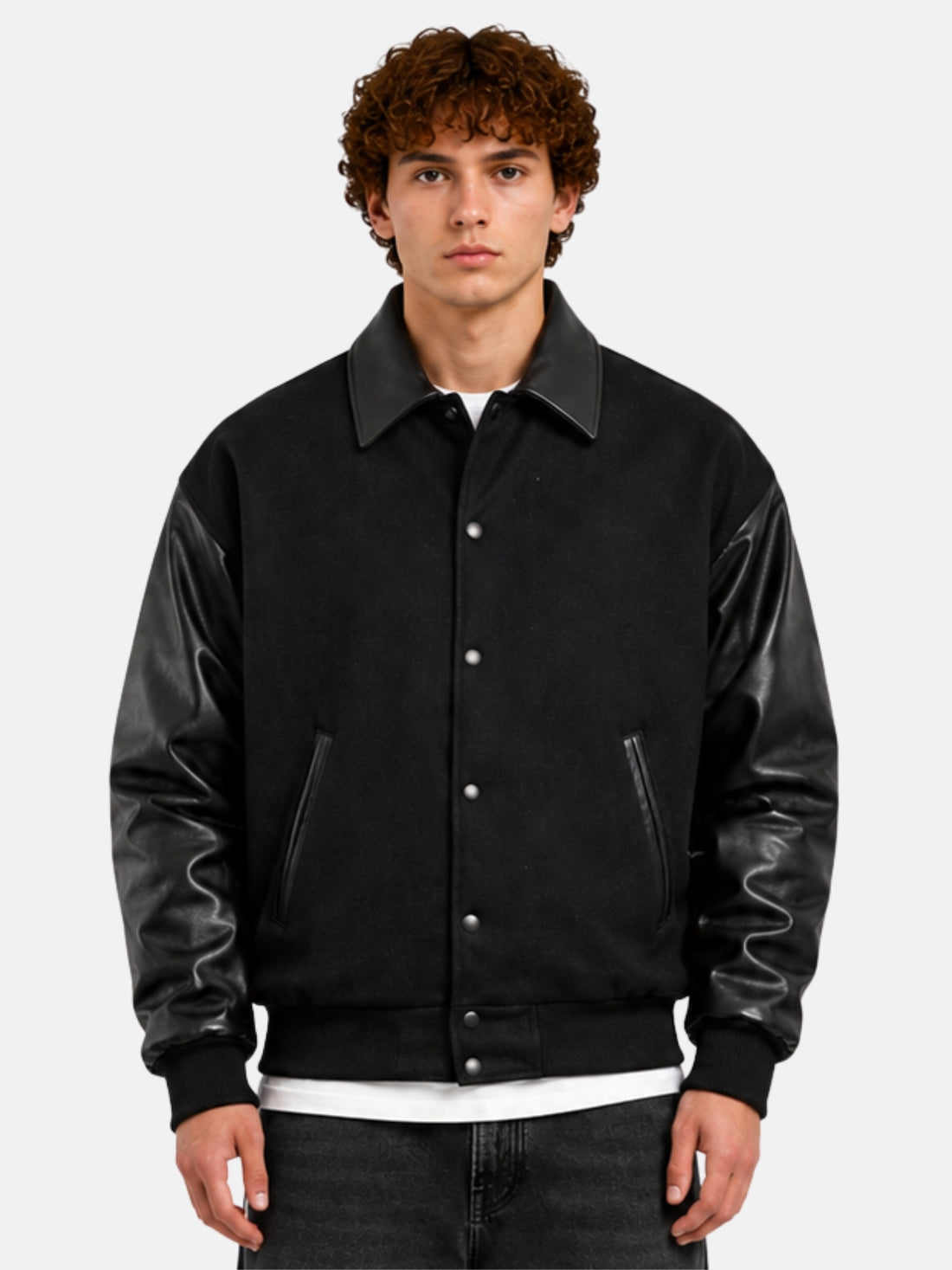 Man wearing an all-black oversized varsity jacket with leather collar and snap front