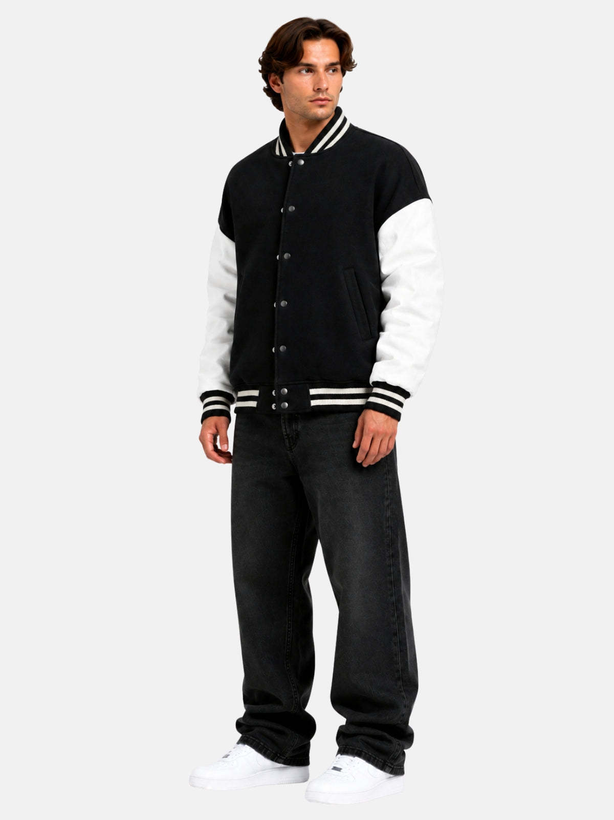 Model in oversized black and white letterman jacket with drop shoulders and baggy jeans