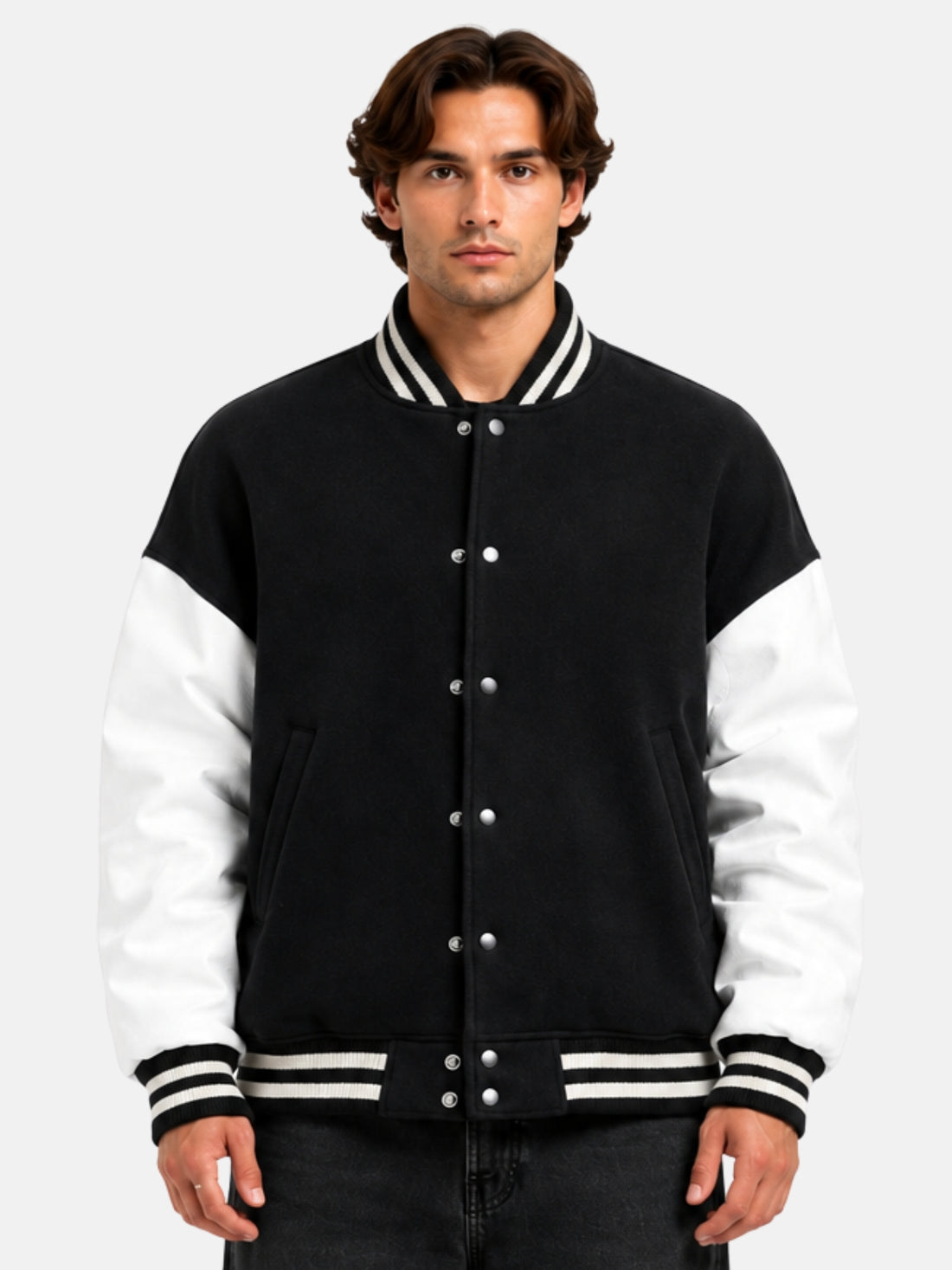 Man wearing oversized black varsity jacket with white leather sleeves and striped rib trims