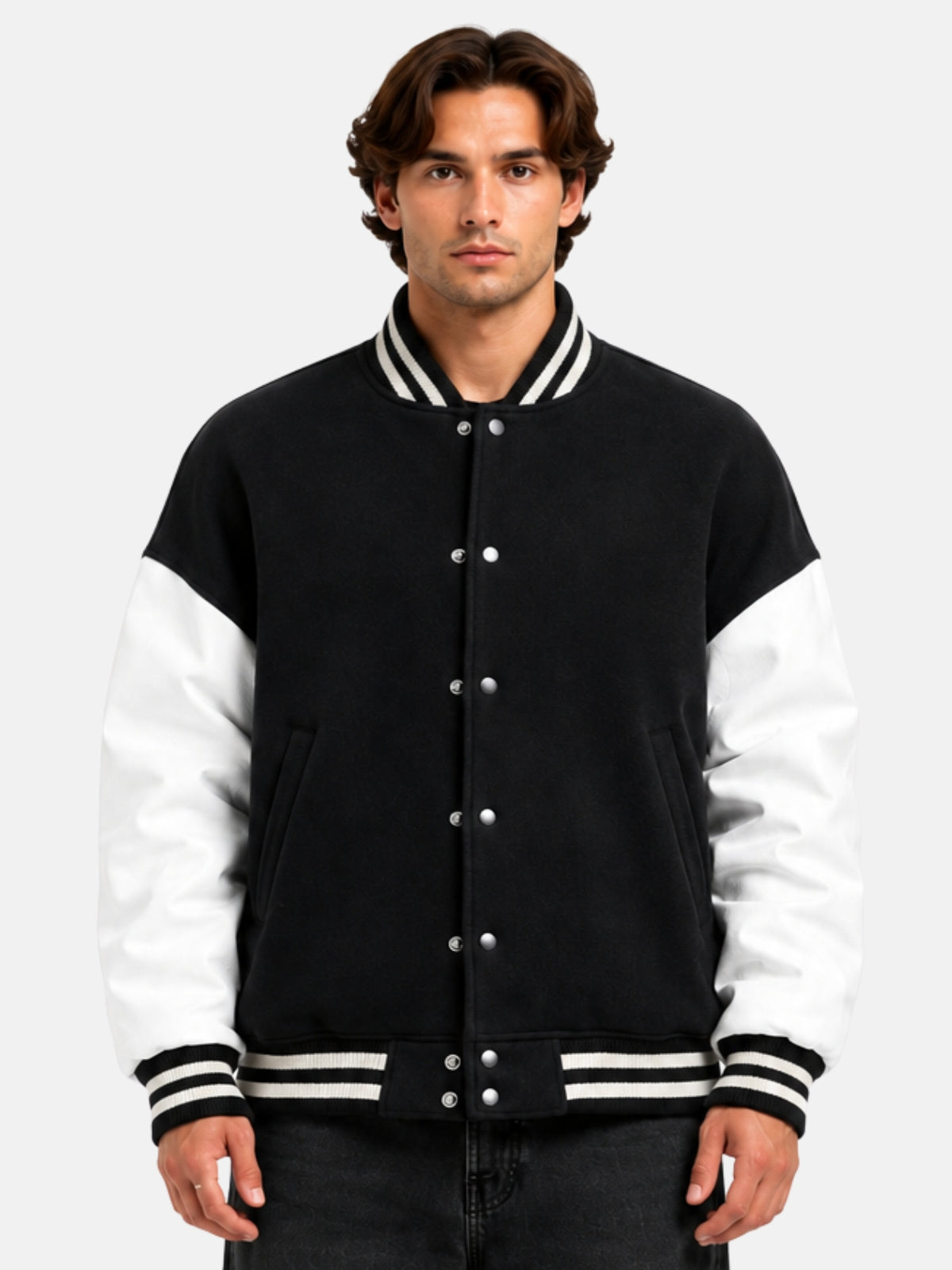 Man wearing oversized black varsity jacket with white leather sleeves and striped rib trims