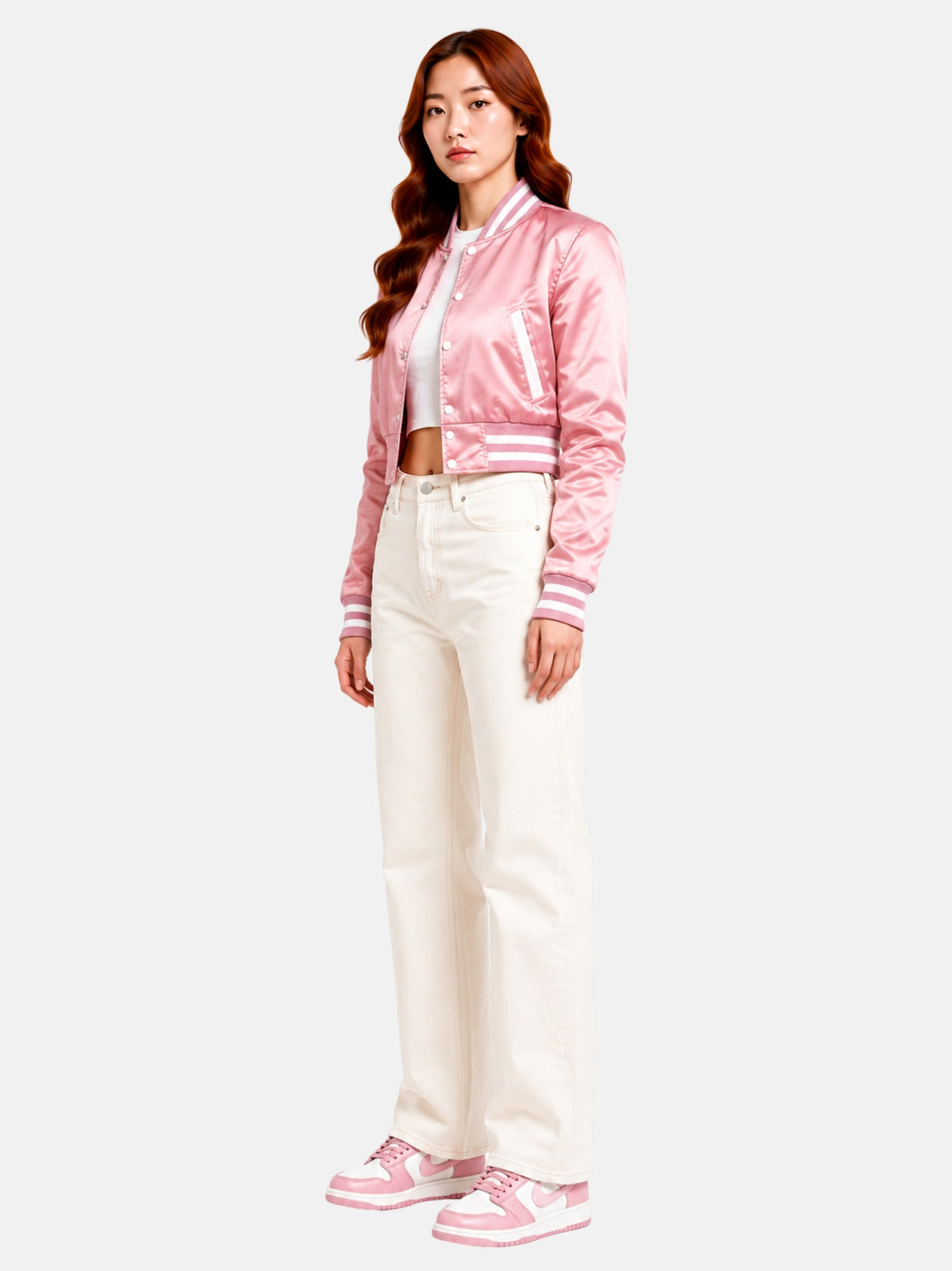 Full-body three-quarter shot of model walking in the pink satin jacket, pink-and-white sneakers and cream denim
