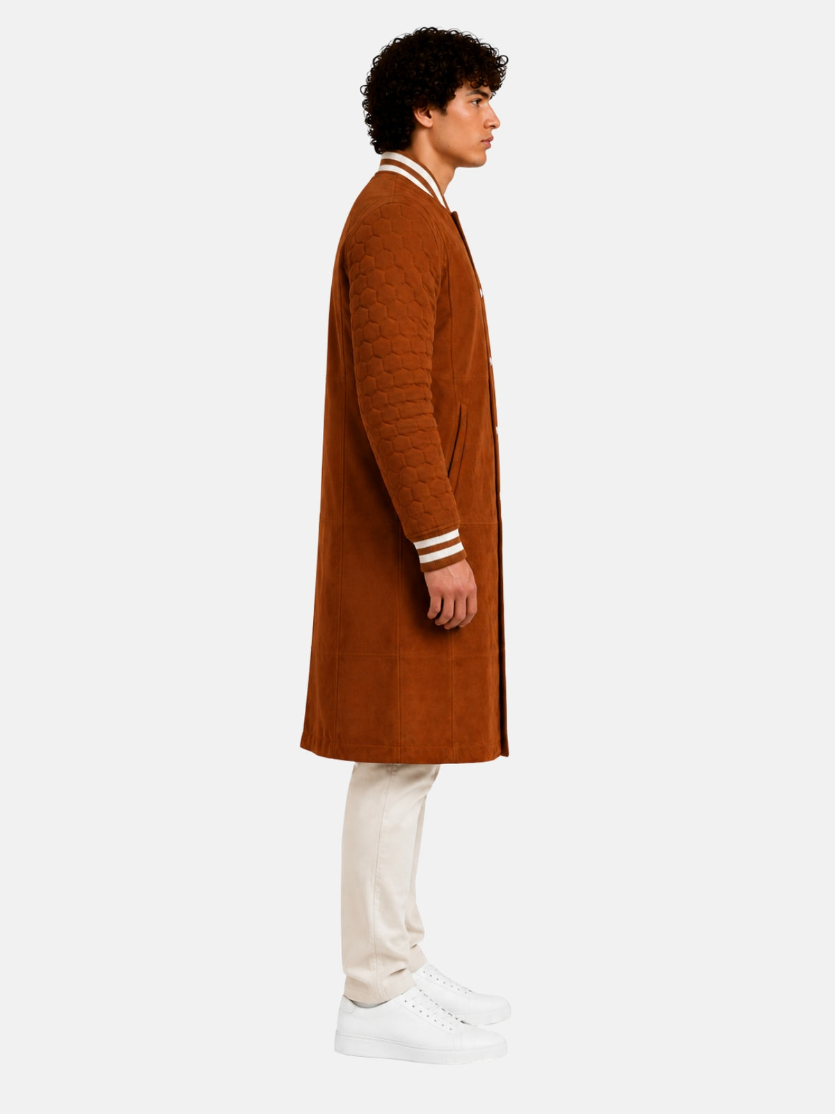 Side profile of tan suede varsity coat showing hex-quilted sleeve and striped knit cuff