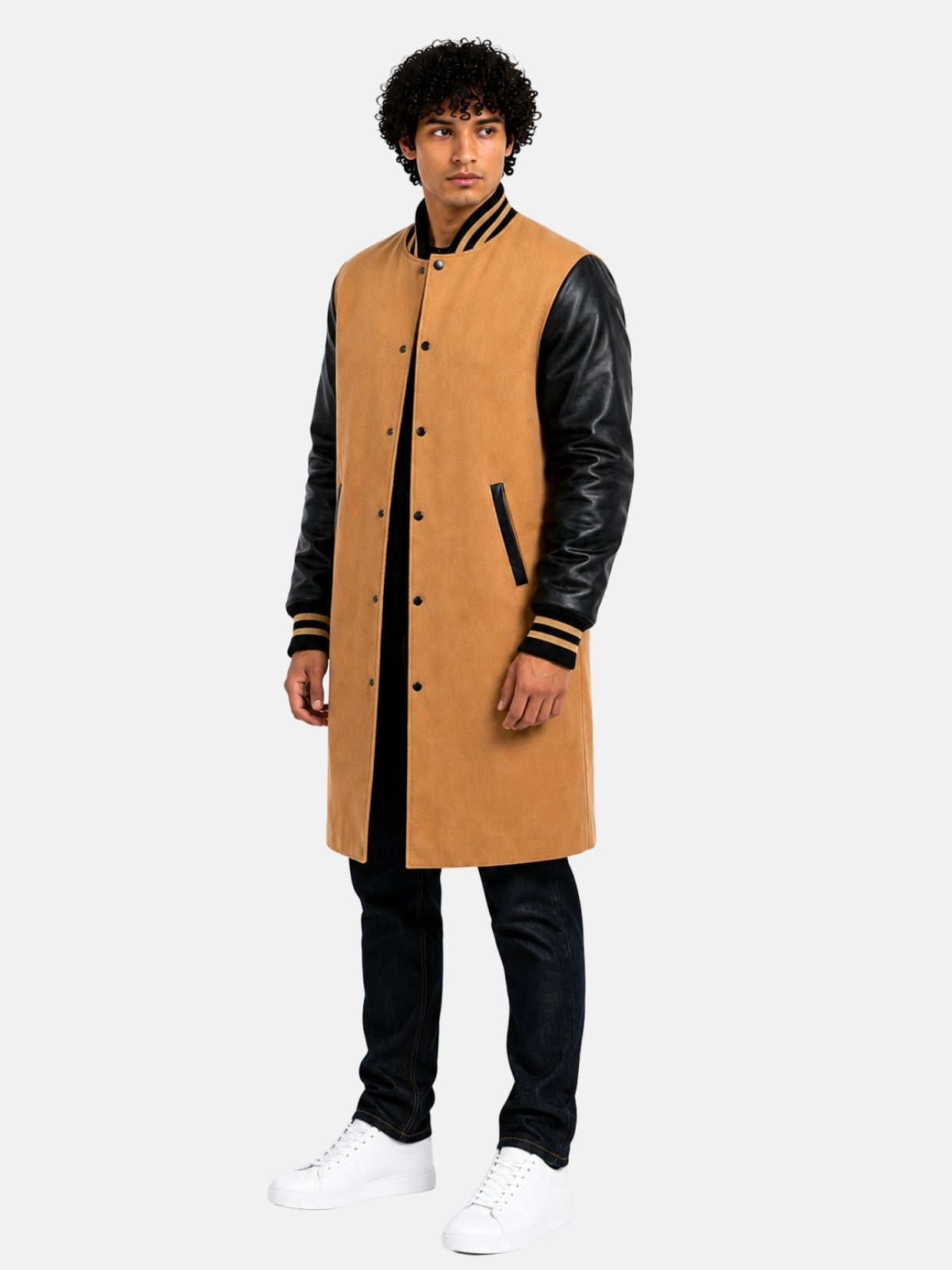 Model in knee-length tan varsity trench coat with black leather sleeves over dark denim
