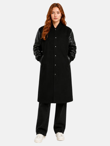 Woman wearing a black longline varsity coat with black leather sleeves, front open